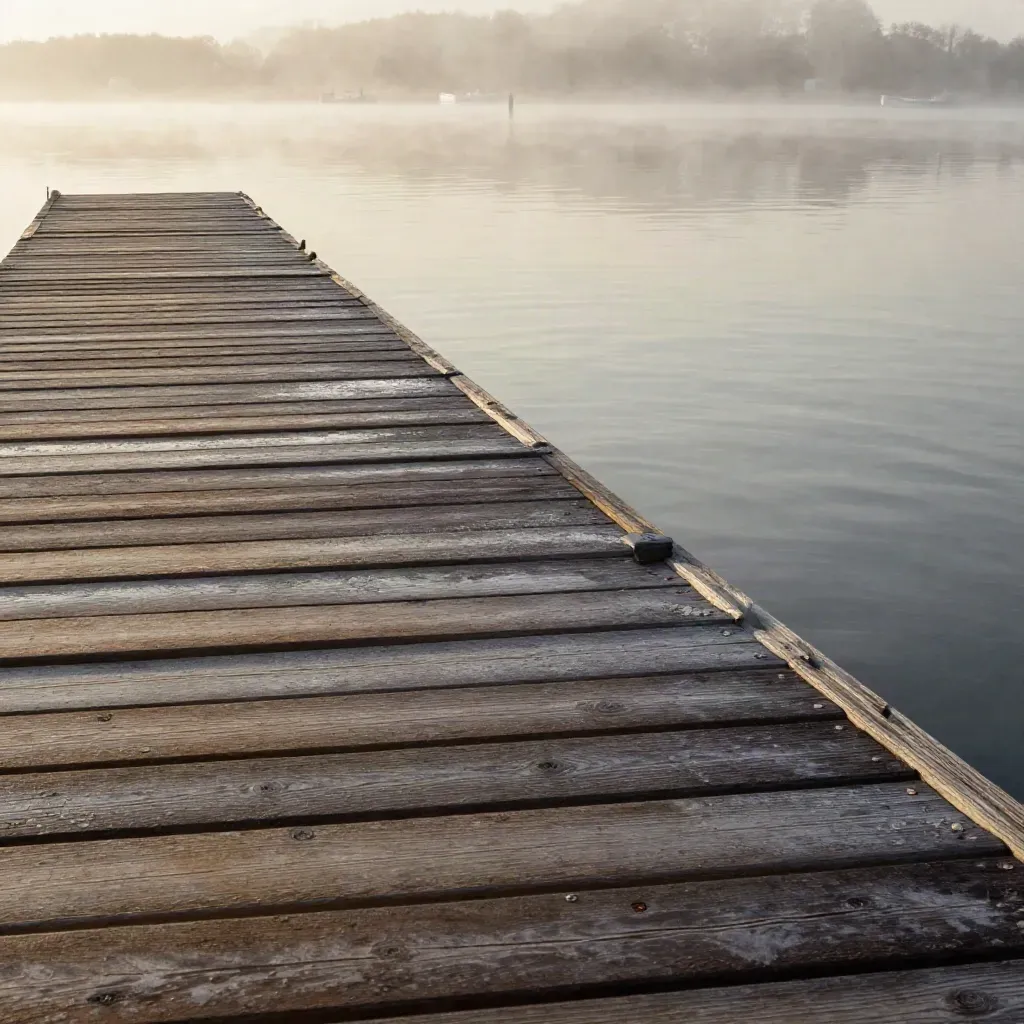 Mälarbrygga i morgondimma med kort spöspets och stilla båtspeglingar